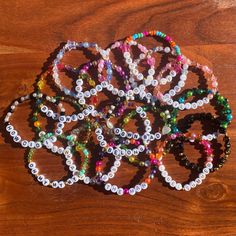 several bracelets are arranged on top of a wooden table, each with different colored beads