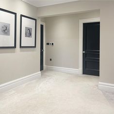 an empty room with pictures hanging on the wall and two black doors in between them