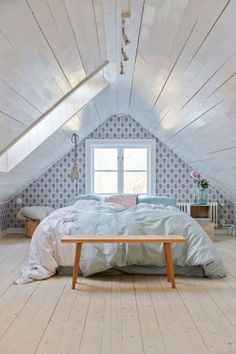 an attic bedroom with white walls and wood floors