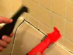 a person holding a red and black toothbrush in front of a white tiled wall