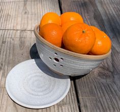 a bowl filled with oranges sitting on top of a wooden table