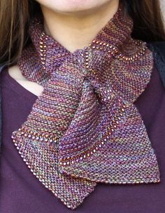 a close up of a woman wearing a purple shirt and a knitted neck scarf