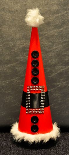 a red traffic cone with black buttons and white fur around it's edges, on a gray surface