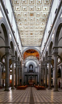 the inside of a church with high ceilings and columns on both sides, looking up at the pews