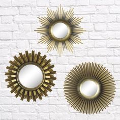 three gold sun mirrors on a brick wall