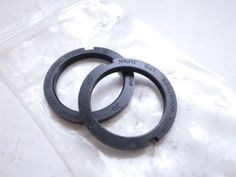 two black metal rings sitting on top of a plastic bag next to eachother