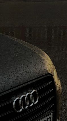 the front end of an audi car with rain drops on it