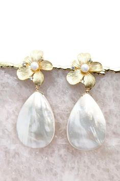 These statement bridal earrings will turn heads as you walk down the aisle. Featuring mother of pearl teardrop earrings with a gold flower stud base. Classic and modern wedding jewelry for brides, bridesmaids, and mother of brides. Wear these pearl teardrop wedding earrings for your rehearsal dinner, bridal shower, and your wedding for a touch of timeless elegance. Shop all your bridal jewelry needs at shopkateandmari.com. Chic Teardrop Pearl Earrings For Party, Glamorous Teardrop Pearl Earrings, Glamorous Teardrop Pearl Earrings For Pierced Ears, Chic Silver Teardrop Pearl Earrings, Chic White Teardrop Pearl Earrings, Teardrop Pearl Earrings For Party, Chic Teardrop Pearl Earrings For Pierced Ears, Teardrop Mother Of Pearl Wedding Earrings, Modern Wedding Jewelry