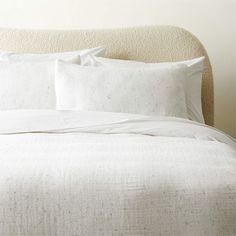 a bed with white sheets and pillows on it