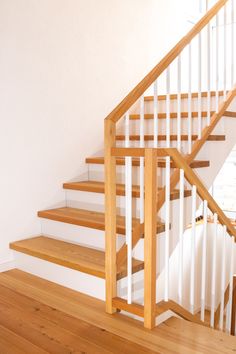 there is a wooden stair case next to the banister in this house with white walls and wood floors