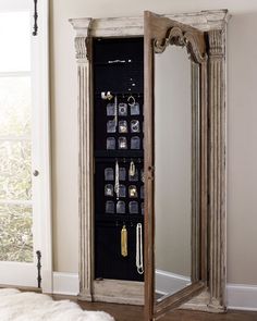 a mirror that is next to a wall with jewelry hanging on it and an armoire in the corner