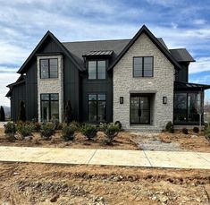 a house that is being built in the middle of some dirt and grass with bushes around it