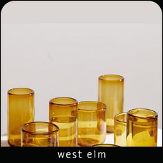 several yellow glass cups sitting on top of a white countertop next to each other