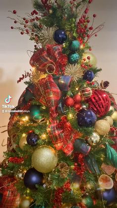 a christmas tree with ornaments and lights on it's top is decorated in red, green and blue