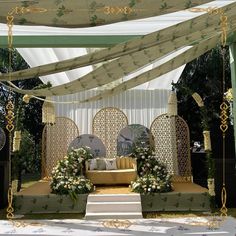 an outdoor wedding setup with white flowers and greenery on the stage, decorated with gold trimmings