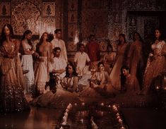 a group of people standing and sitting around each other in front of some lit candles