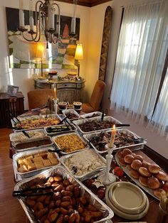 a table filled with lots of food on top of a hard wood floor next to a chandelier