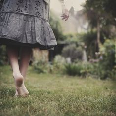 a woman walking across a lush green field