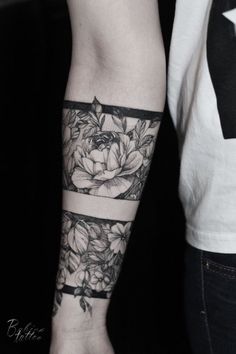 a woman's arm with flowers on it and a black ribbon around the wrist