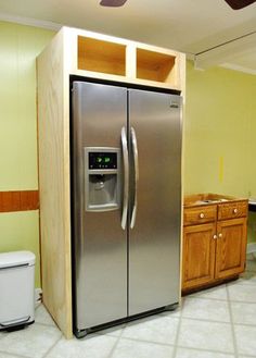 a stainless steel refrigerator and freezer combo in a kitchen with yellow walls, white tile flooring and wooden cabinets