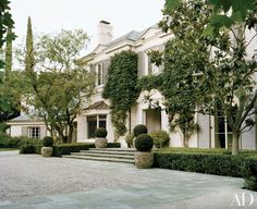 a large white house surrounded by trees and bushes