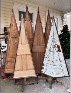 three wooden christmas trees sitting next to each other on top of pallets in front of a house