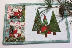 a quilted placemat with christmas trees on it and pine cones in the center