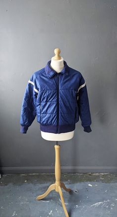 Guys, if your love for all things snow runs retro in style, then grab that 80s vibe with this vintage skiing jacket! Made by Rodeo (by C&A) Chunky zip up front Stretch ribbing hem and cuffs Two front pockets, and one inside pocket. 65% polyester, 35% cotton outer shell 100% Nylon lining 100% polyester wadding Labelled a 38, this fits a mens Medium = 40 inch (101 cm) to 42 inch (107 cm) chest Garment Measurements: Chest= 44 inches (112 cm) Waist= 42 inches (107 cm) Hips/hem= 34-44 inches (86 to 112 cm) Length shoulder to hem= 24 inches (61 cm) In great vintage condition- some slight bobbling on the inside ribbing on the hem. Casual Skiing Outerwear With Fleece Lining, Retro Long Sleeve Windbreaker For Winter, Sporty Outerwear For Ski Season, Vintage Windbreaker For Winter Sports With Pockets, Vintage Windbreaker For Fall Winter Sports, Vintage Hooded Windbreaker For Skiing, Vintage Windbreaker For Ski Season, Vintage Blue Windbreaker For Winter, Vintage Skiing Outerwear With Pockets