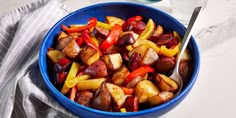 a blue bowl filled with cooked vegetables next to a glass of water and a spoon