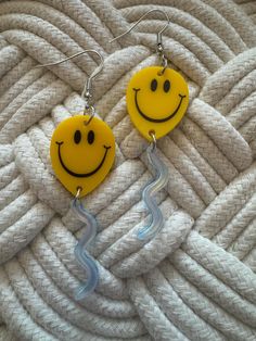 two yellow smiley face earrings on top of a white roped surface with a hook in the middle