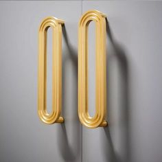 two gold metal handles on a gray wall next to a door with the letter o