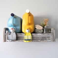 there are three different colored jugs on the shelf next to each other and one is yellow