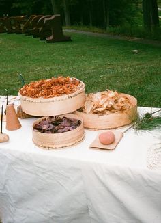 a table topped with wooden bowls filled with food next to a park bench in the background