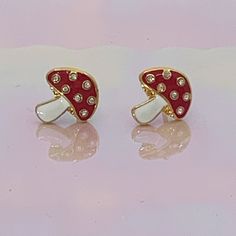 "Add some magic with our adorable dainty Mushroom Stud Earrings! Beautifully detailed with red enamel, sparkling crystals, & plated gold. ♥ Measures approx. ⅜ \" ♥ Materials: dipped in gold plating, glitter flooded resin, & enamel. Posts are titanium - good for sensitive ears! ♥ Packaged in our cute gift box ♥ Designed by & exclusive to Wildflower + Co. ♥ Imported ♥ Product safety - intended for use by adults only; CA residents - see shop policies for Prop 65 warning ♥ Includes 1 pai Gift Gold Earrings With Mushroom Design, Whimsical Gold Earrings With Mushroom Design, Red Mushroom Design Jewelry Gift, Whimsical Gold Mushroom Earrings, Mushroom Stud Earrings, Earrings Mushroom, Aesthetic Earrings, Mushroom Earrings, Earrings Aesthetic