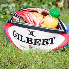 a rugby ball sitting in the grass with a bottle of water on top of it