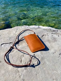 a brown purse sitting on top of a rock next to the ocean