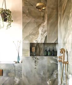 a bathroom with marble tiles on the walls and floor, including a shower head in the corner