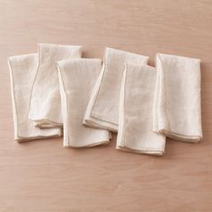 four folded white napkins sitting on top of a wooden table