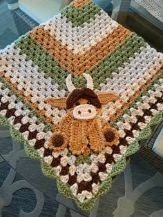 a crocheted blanket with a stuffed animal on it sitting on top of a table