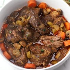 a white bowl filled with beef and carrots