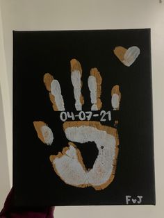 a person holding up a black and orange handprint with white letters that read 0 00 - 2