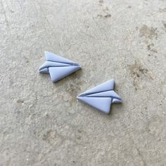 two origami airplanes sitting on top of a cement floor next to each other