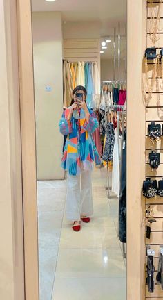 a woman taking a selfie in front of a closet full of clothes and accessories