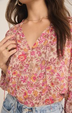 Add a dose of bright florals to your wardrobe with the Carine Lima Floral Top from Z Supply. This flowy, v-neck top features a vibrant floral print that will instantly refresh your look. The 3/4 blouson sleeves + ruffle collar detail add a touch of femininity + elegance, making it a standout piece. The tie detail at the neckline offers versatility + a playful finish. Crafted from lightweight fabric, this top is perfect for both work + play. Pair it with your favorite denim for a casual outing or Icon Jewelry, Flower Branding, Hair Socks, Bright Florals, Flower Tops, Cactus Flower, Ruffle Collar, Mink Pink, Ladies Boutique