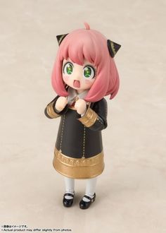 a doll with pink hair and green eyes is holding a pen in her hand while standing on a white surface