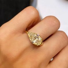 a woman's hand holding a yellow diamond ring