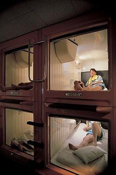 two people are sitting in the windows of a room with bunk beds on each side