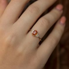 a woman's hand with a ring on it and an orange stone in the middle