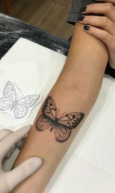 a woman's arm with a butterfly tattoo on the left side of her arm