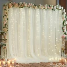 a white wedding backdrop with flowers and candles